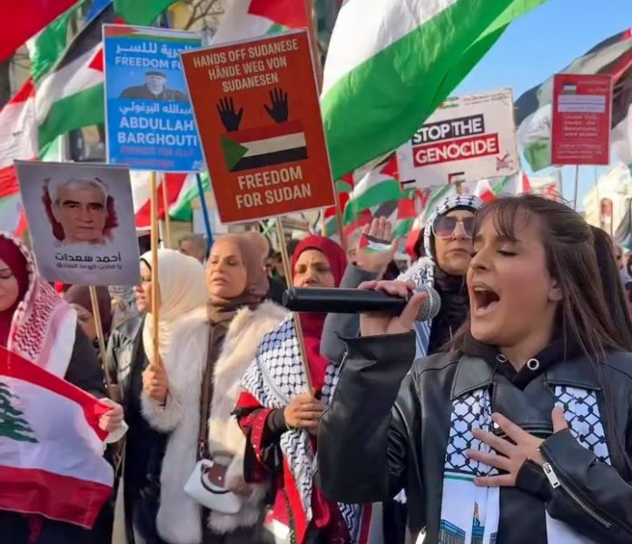 Una manifestante encabezando la movilización de ayer en Berlín | Captura de pantalla de video de @Ryad.Aref en Ig. Una manifestante encabezando la movilización de ayer en Berlín | Captura de pantalla de video de @Ryad.Aref en Ig.