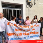 La familia, acompañada por vecinos y vecinas del edificio, se concentra frente a su portal tras una pancarta que reza: “En el nombre de Dios, basta ya de desahuciar a las familias. Las personas son lo primero” | Dominic D. Skerrett