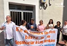 La familia, acompañada por vecinos y vecinas del edificio, se concentra frente a su portal tras una pancarta que reza: “En el nombre de Dios, basta ya de desahuciar a las familias. Las personas son lo primero” | Dominic D. Skerrett