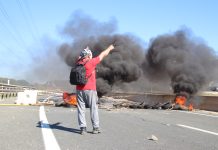 Un trabajador del metal ante una barricada de neumáticos ardiendo durante la primera jornada de huelga indefinida en el Valle de Escombreras, en Cartagena. | Foto: Dominic David Skerrett.